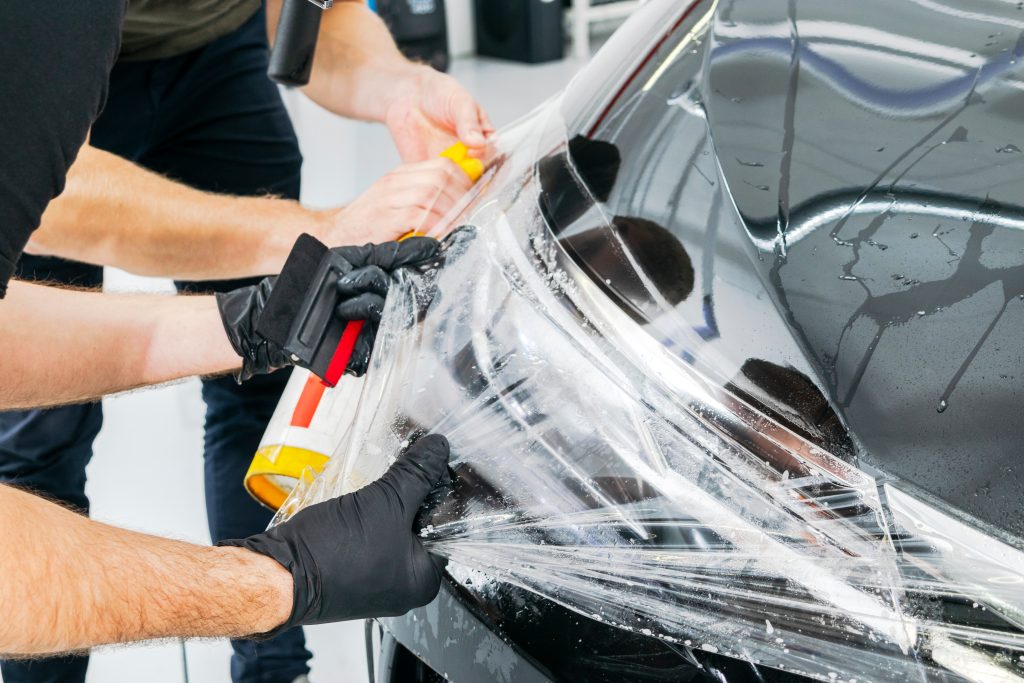 technician applying protective film to a car headlight.