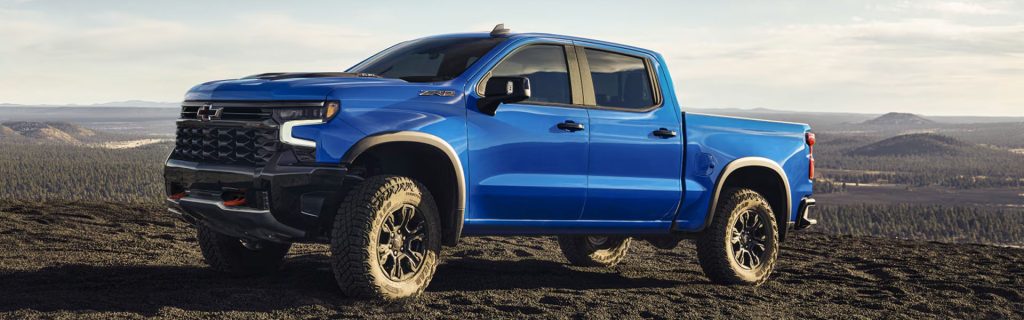 Blue Chevrolet Silverado pickup truck parked on a scenic mountain landscape
