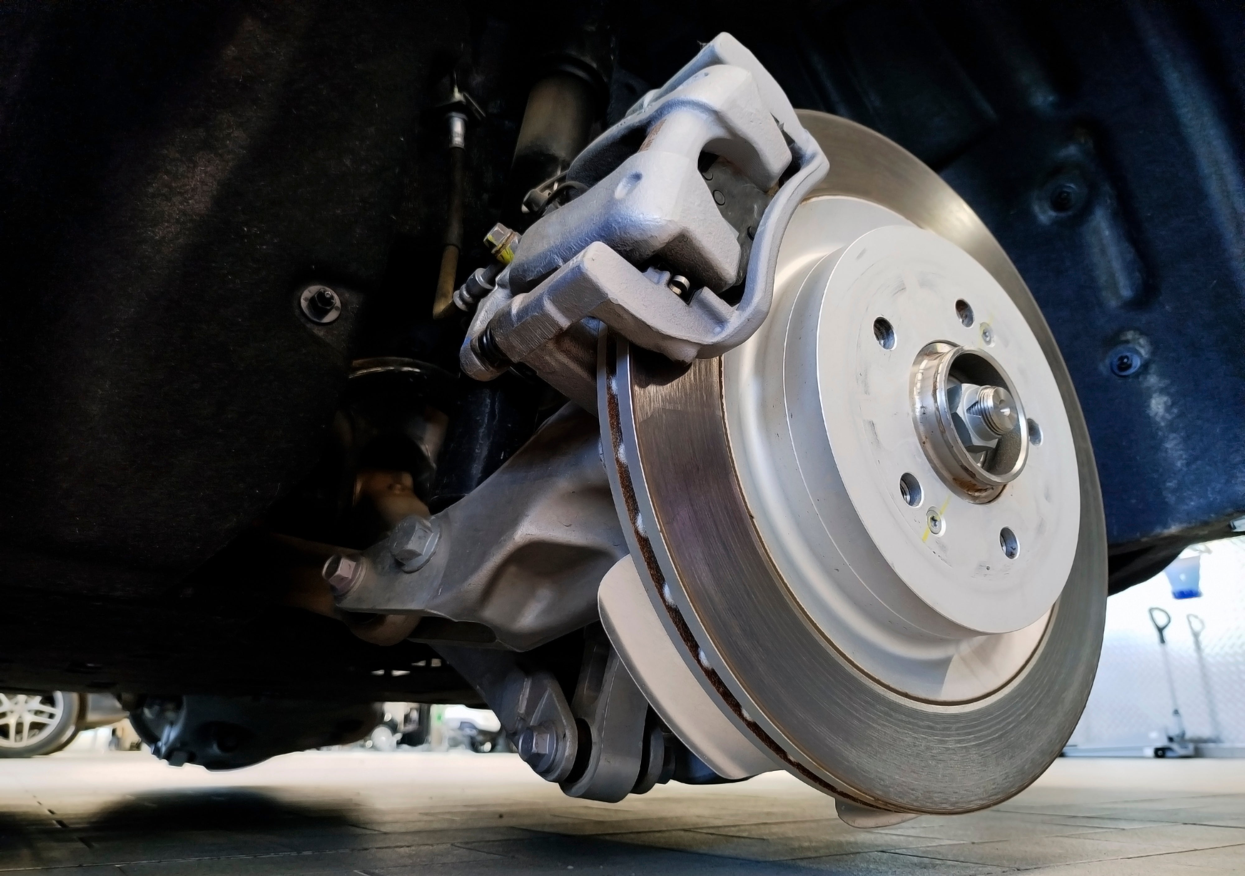 Close-up view of a vehicle brake rotor and caliper assembly during automotive brake service.